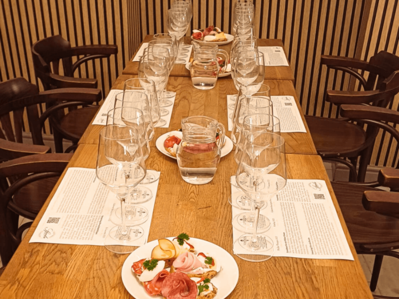 Bratislava: Wine tasting in the city center showcasing a long table set with wine glasses and plates of traditional Slovak appetizers in a welcoming café.