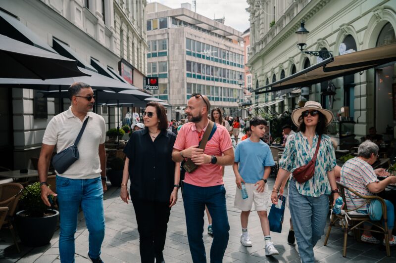 Tourists strolling through the lively streets of Bratislava on a day trip from Vienna. The group enjoys the vibrant atmosphere, passing by cafes and shops in the city center