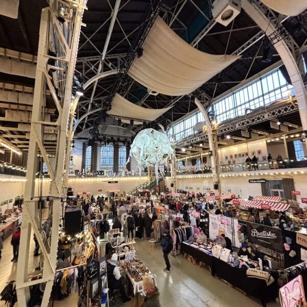 Modern interior of the Bratislava Old Town Market Hall during Christmax Markets, featuring vibrant market stalls, decorations, and the preserved industrial architecture.