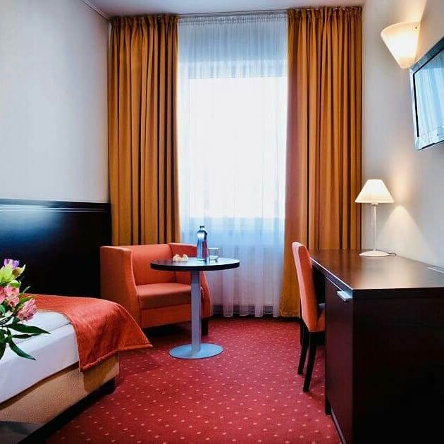 Standard single room at Tatra Hotel Bratislava Old Town with red carpet and orange curtains