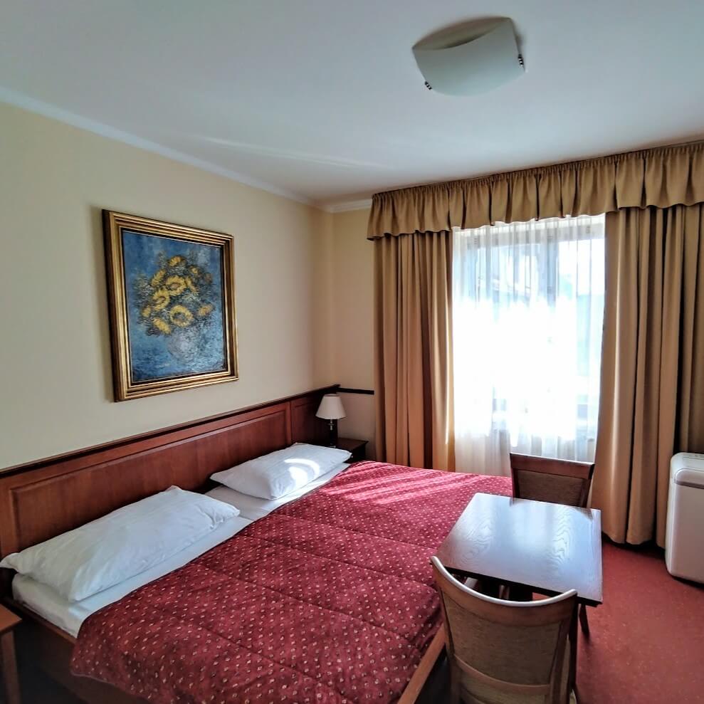 Cosy double room at Matysak Wine Hotel Bratislava with classic wooden furniture and sunflower painting