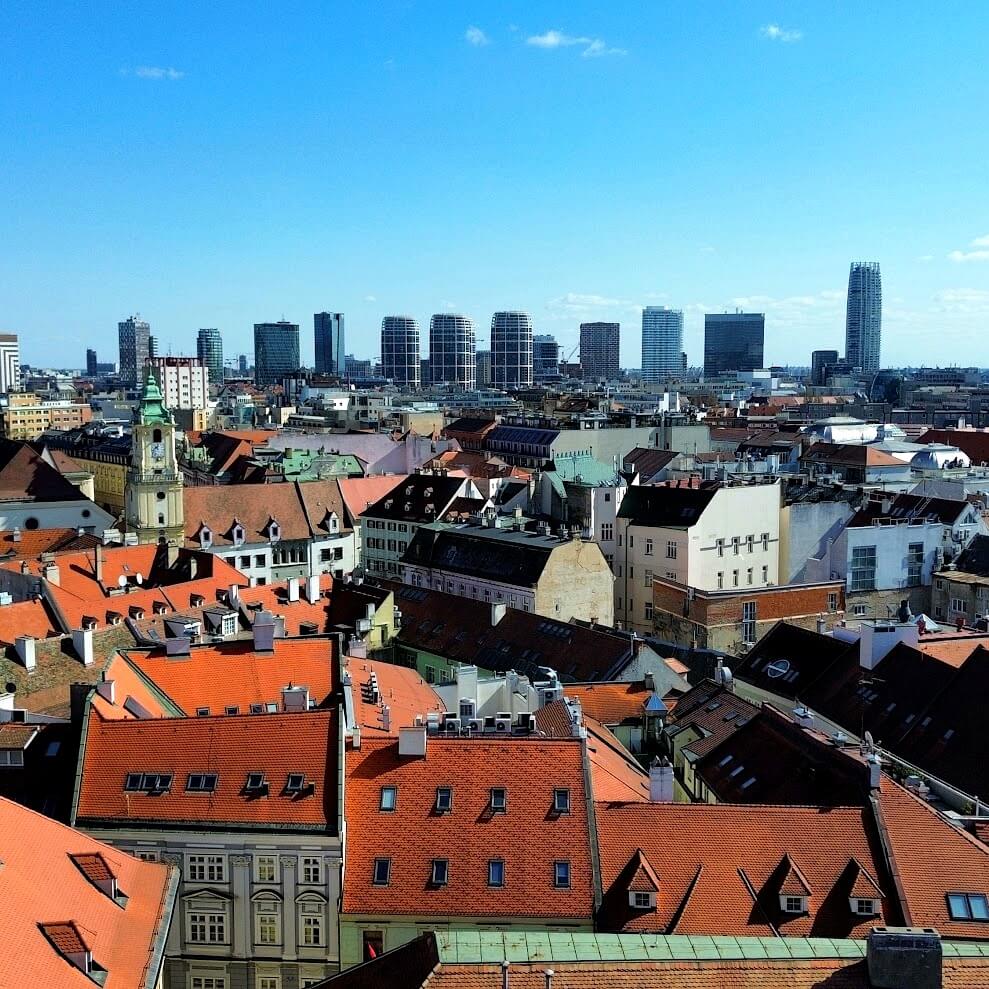 Aerial view of Bratislava Old Town red-tiled rooftops with the modern city skyline and Danube river in the background — a highlight of any 48 hours in Bratislava itinerar