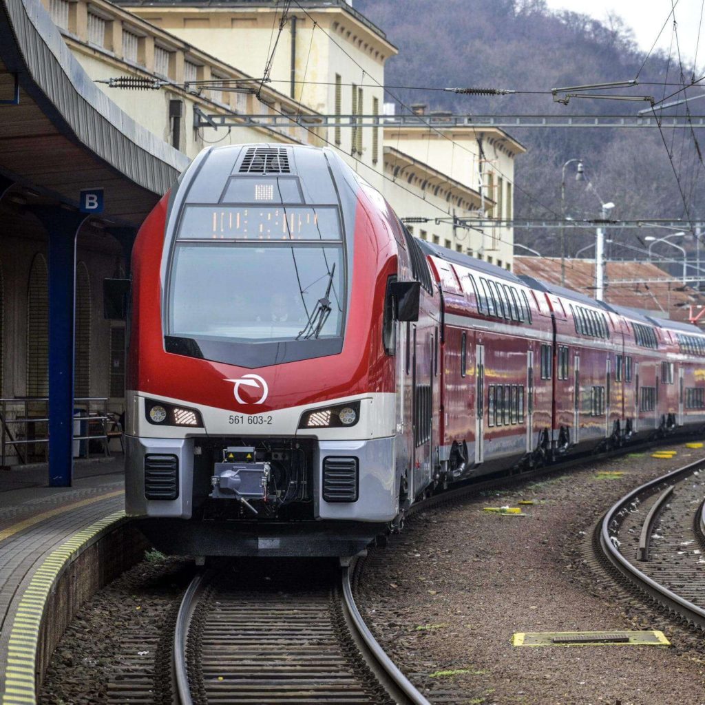 Red ZSSK passenger train on the Bratislava to Budapest railway route through the Slovak mountains