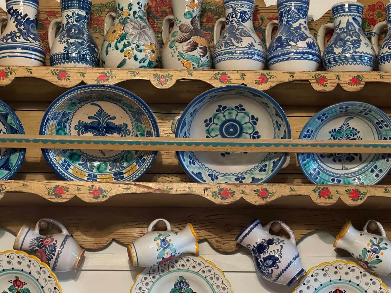 Traditional Slovak Modra pottery with blue floral patterns displayed on painted wooden shelves