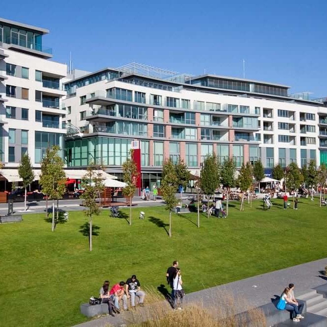 Eurovea shopping district in Bratislava with green park lawn and modern apartment buildings